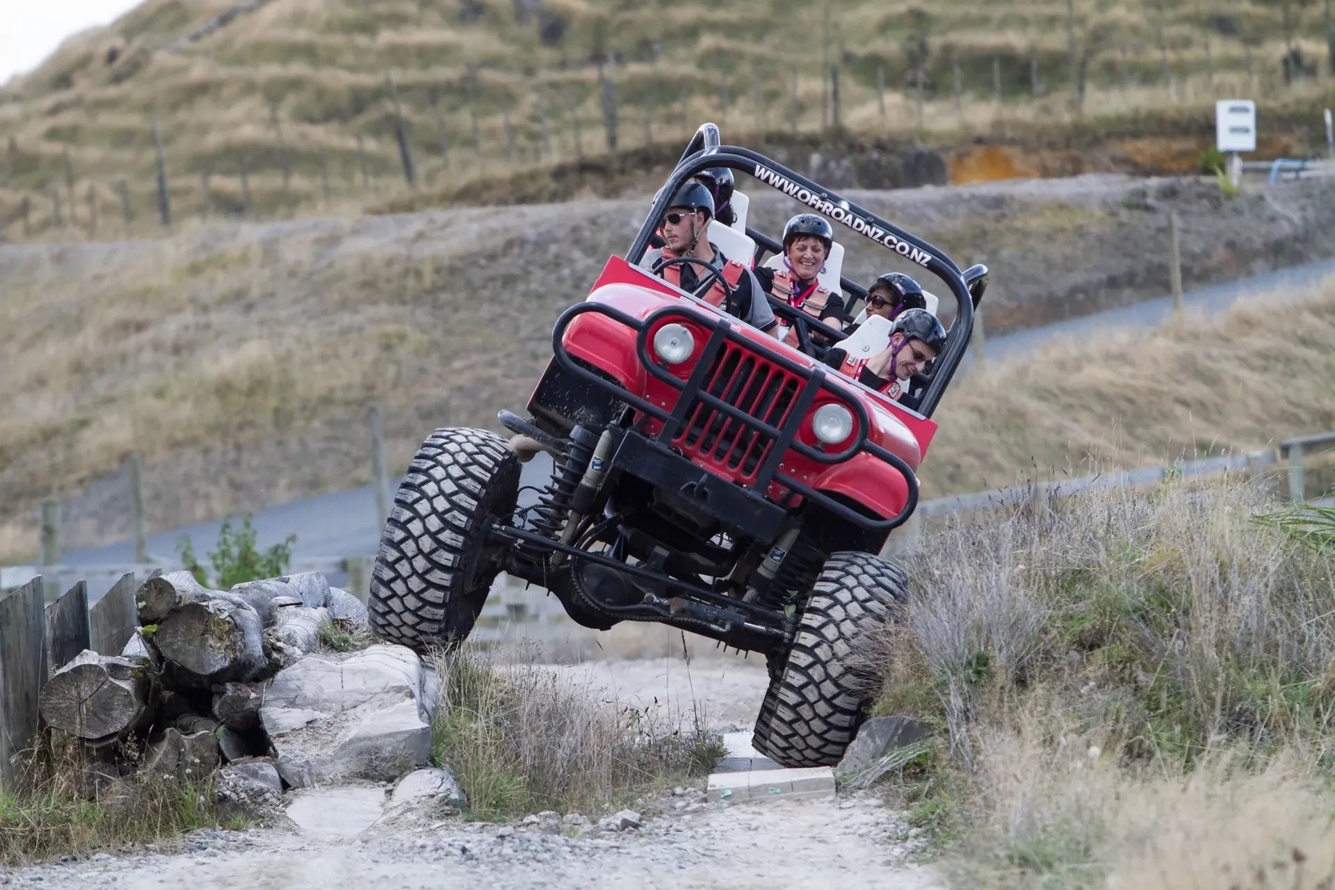 Group of people driving in an off-road car crossing over a rock.