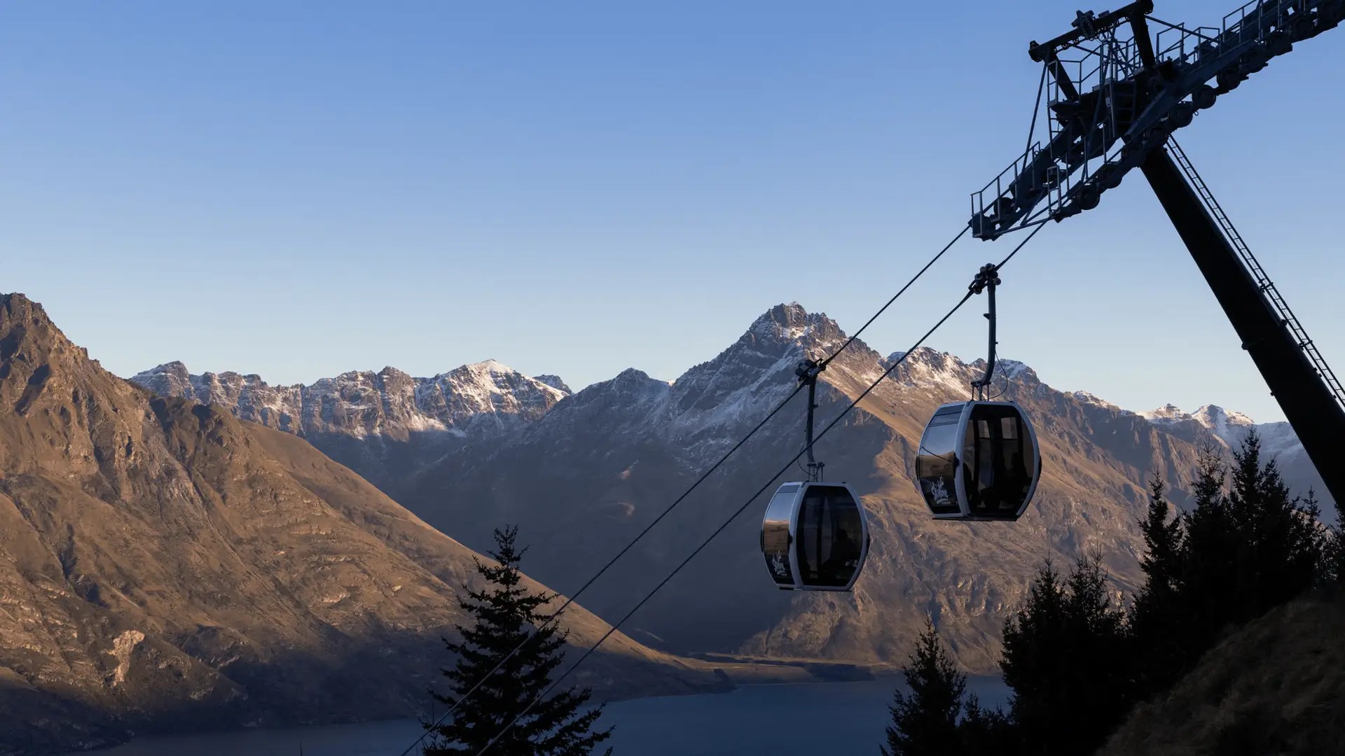 Two Skyline Gondola carriages in shadow, in front of mountains