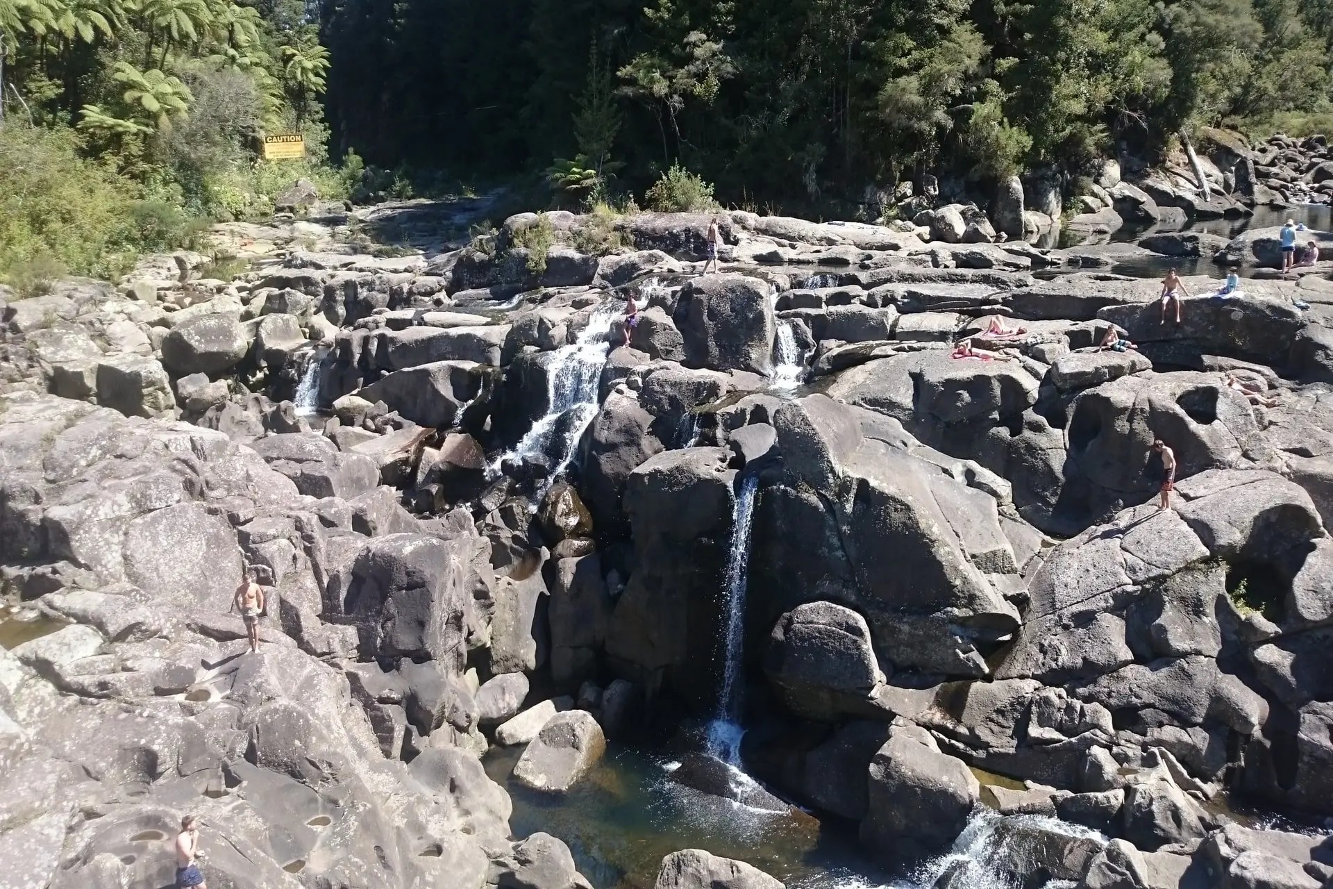 People playing among large rocks and waterfalls at McLaren Falls Park.