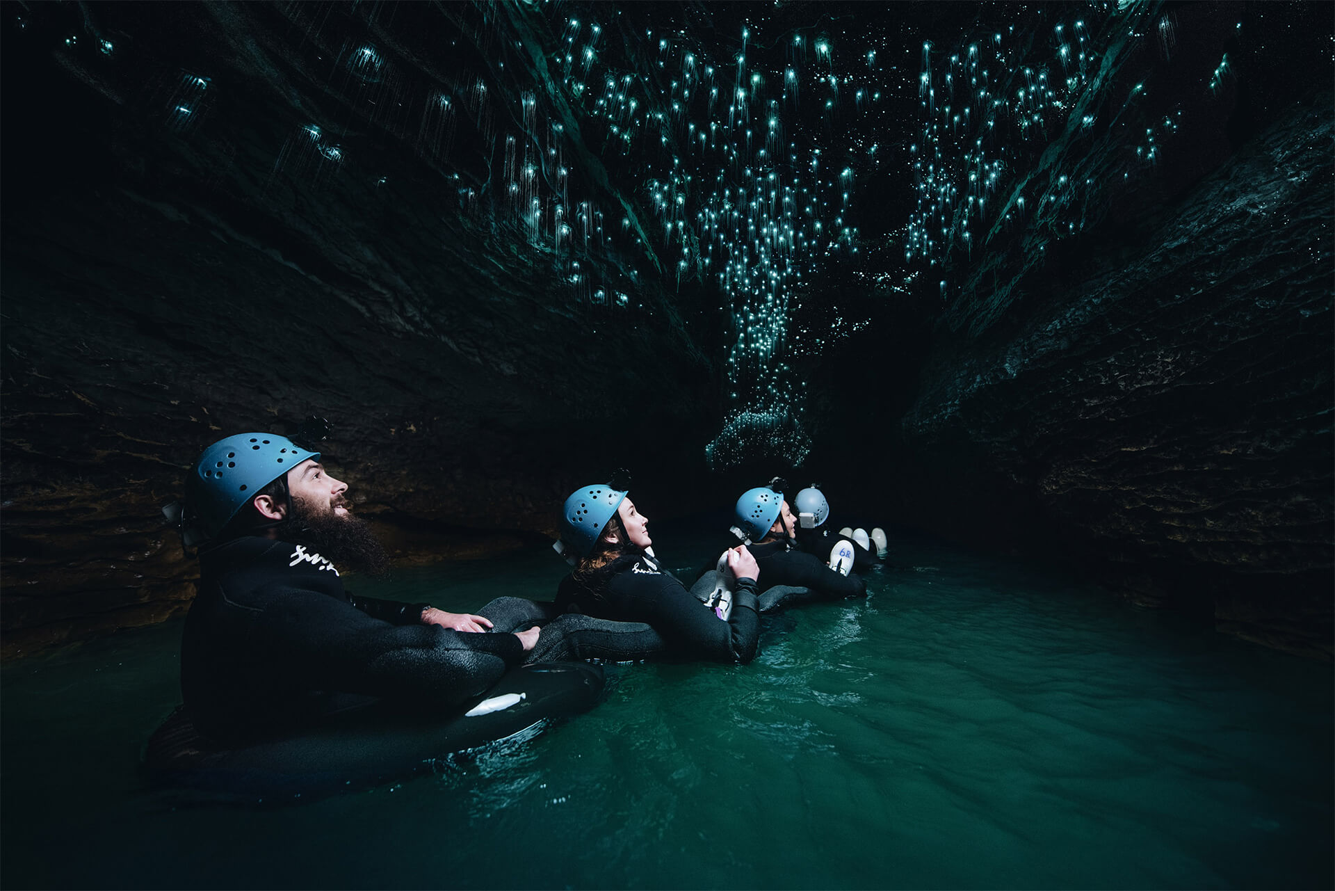 A man walks through a cave at Waitomo illuminated by glow worms .