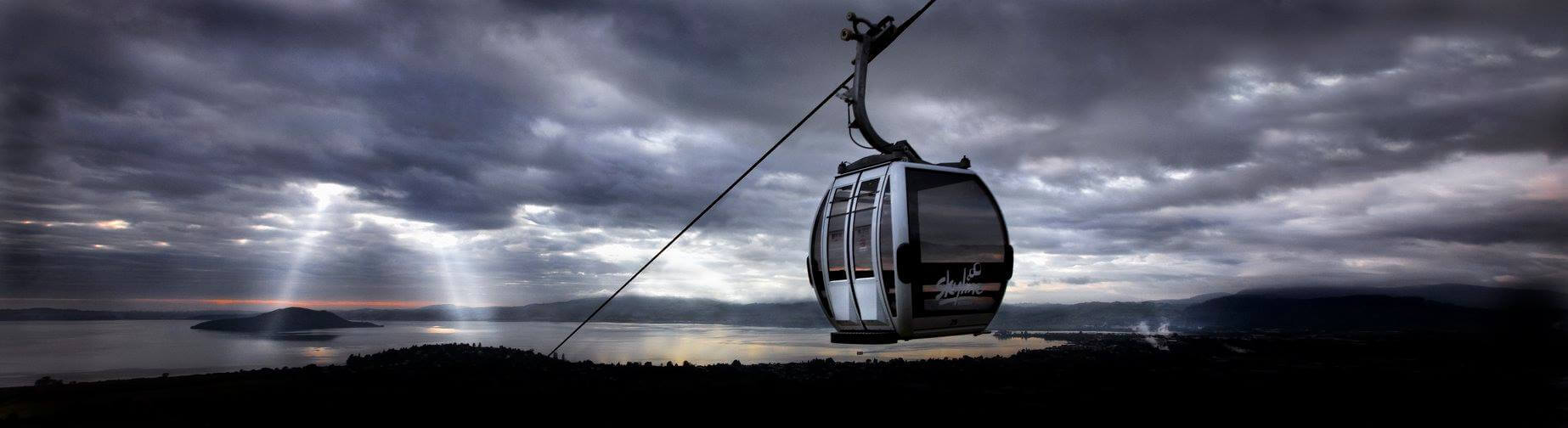 An image of a Gondola cabin with dark grey clouds over Lake Rotorua.