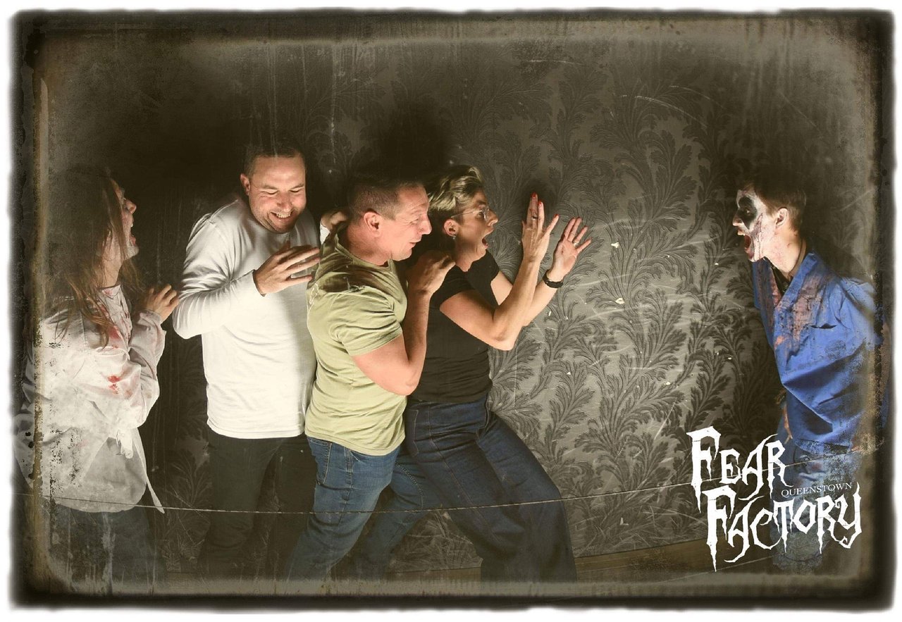 Four friends grab each other as they are scared of a man with clown makeup on at Fear Factory Queenstown.