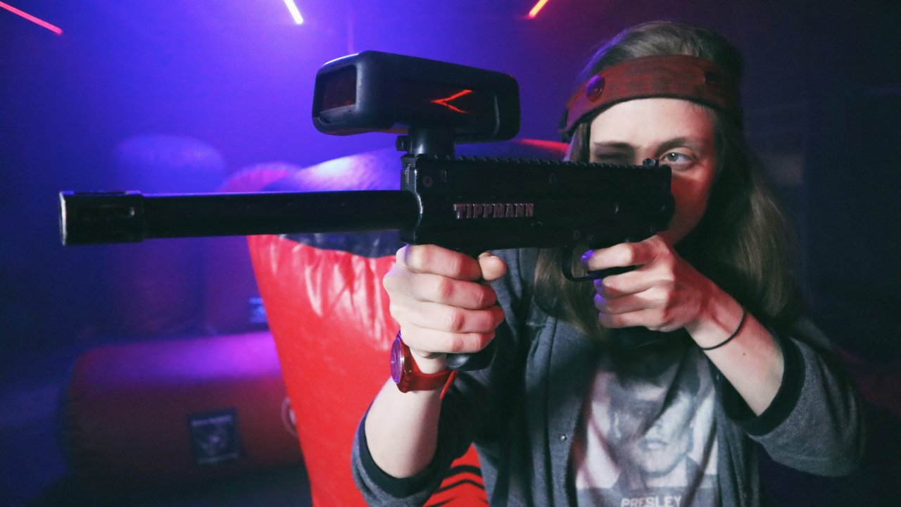 A woman holds a laser gun up to her head as she peers through the scope.