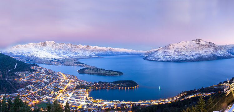 View from Skyline Queenstown of a purple sunset over snow covered Queenstown.