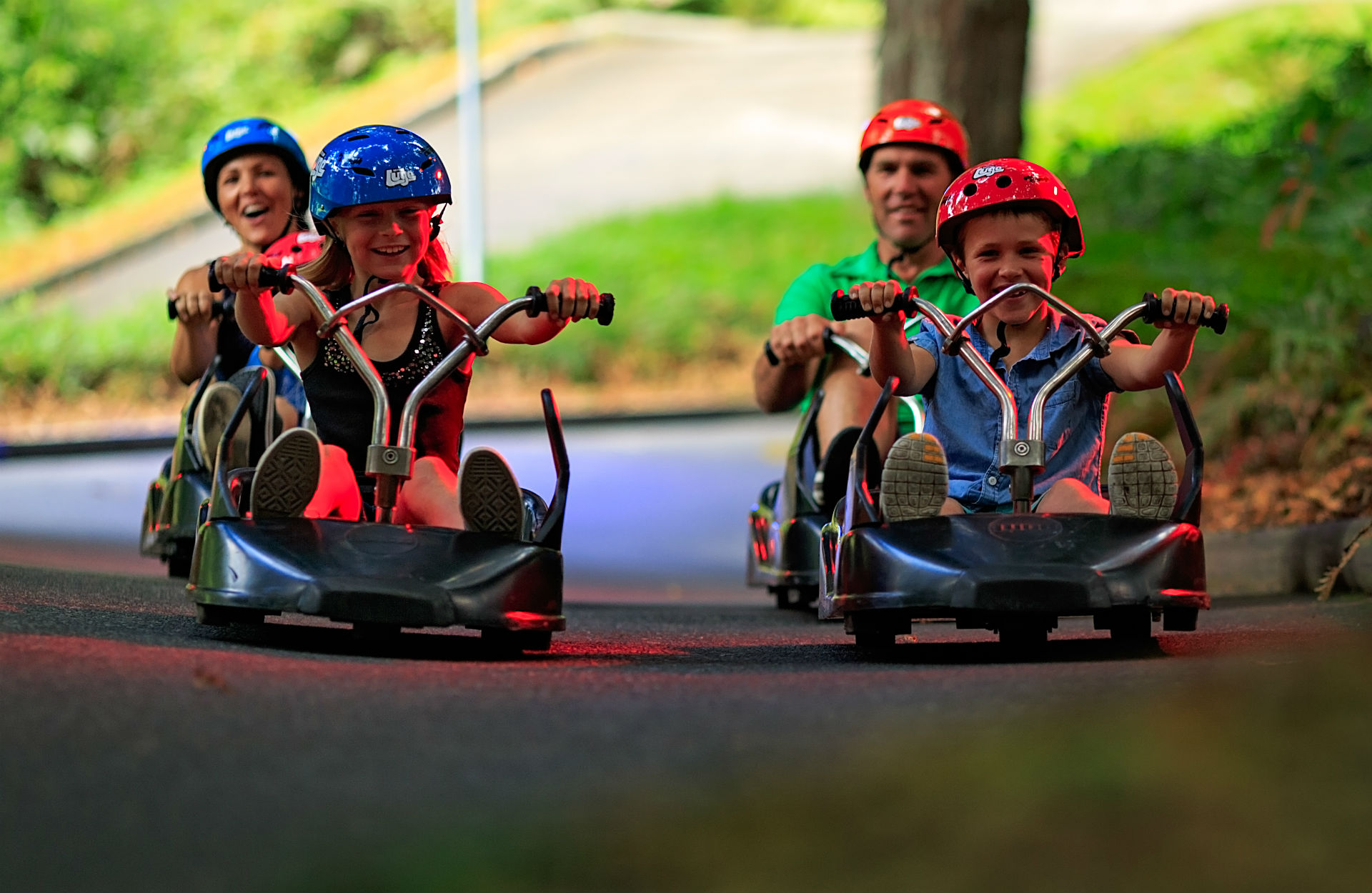 A family rides the Luge together beneath colourful lights.