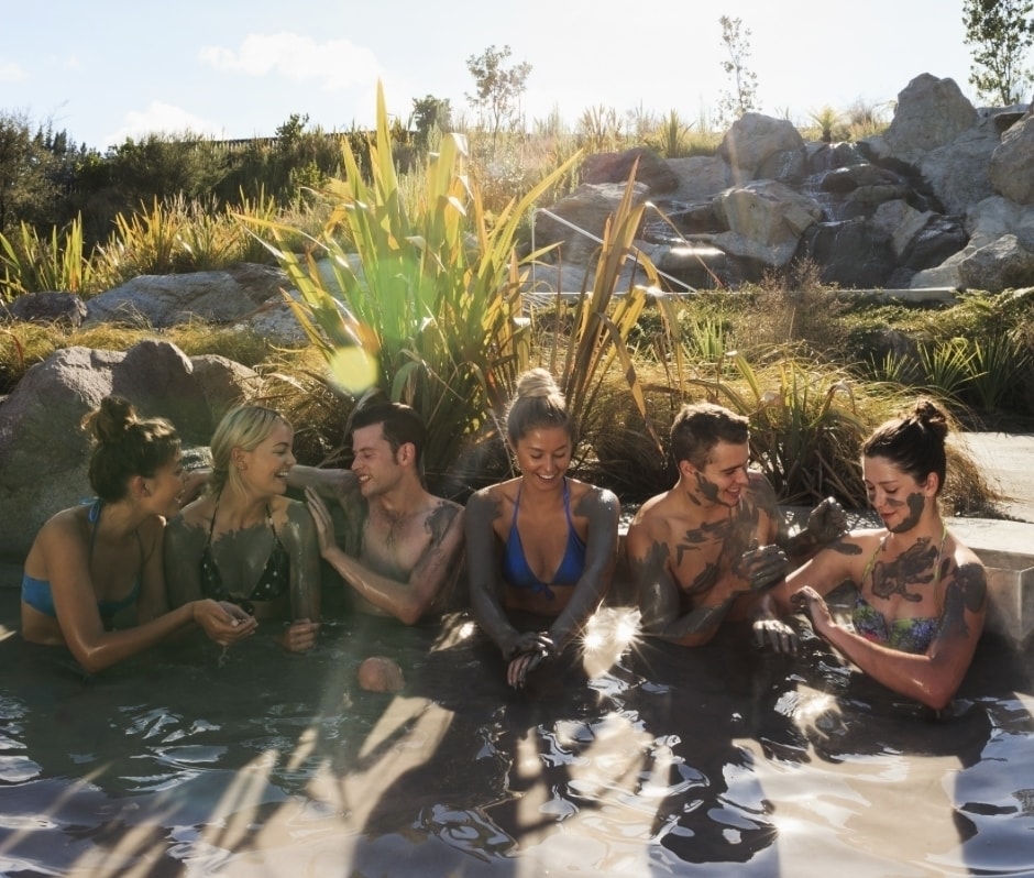 A group A group of friends poses for a photo completely covered in mud at Hell's Gate located in Rotorua.friends enjoying the mud pools at Rotorua's Hells Gates.