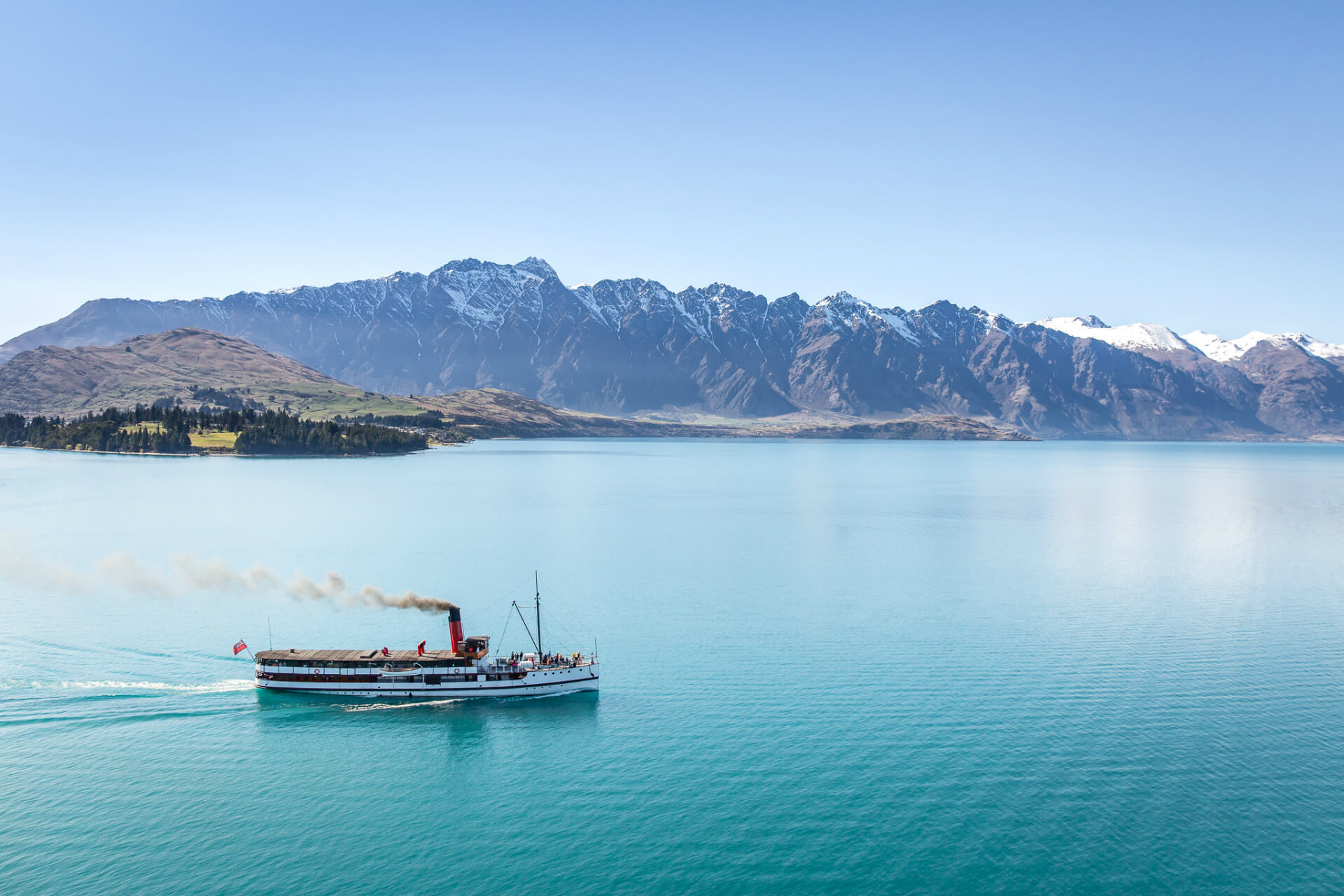 TSS Earnslaw cruise ship moving across Lake Wakatipu with mountains in distant view.