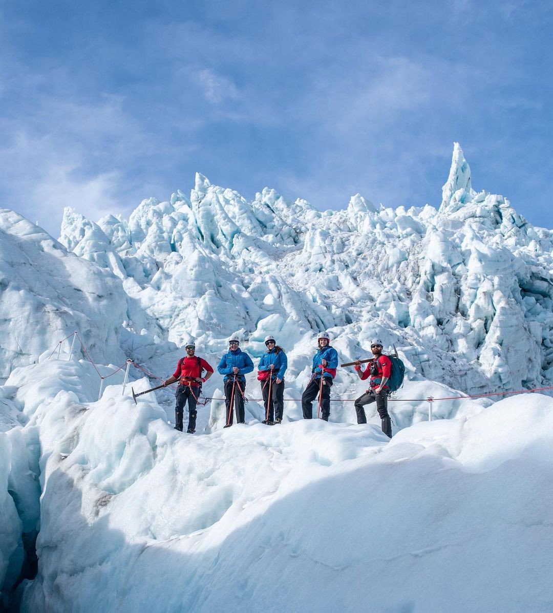 A group of customers and guides pose in front of an upper section of the Franz Josef glacier on the West Coast of New Zealand's South Island.