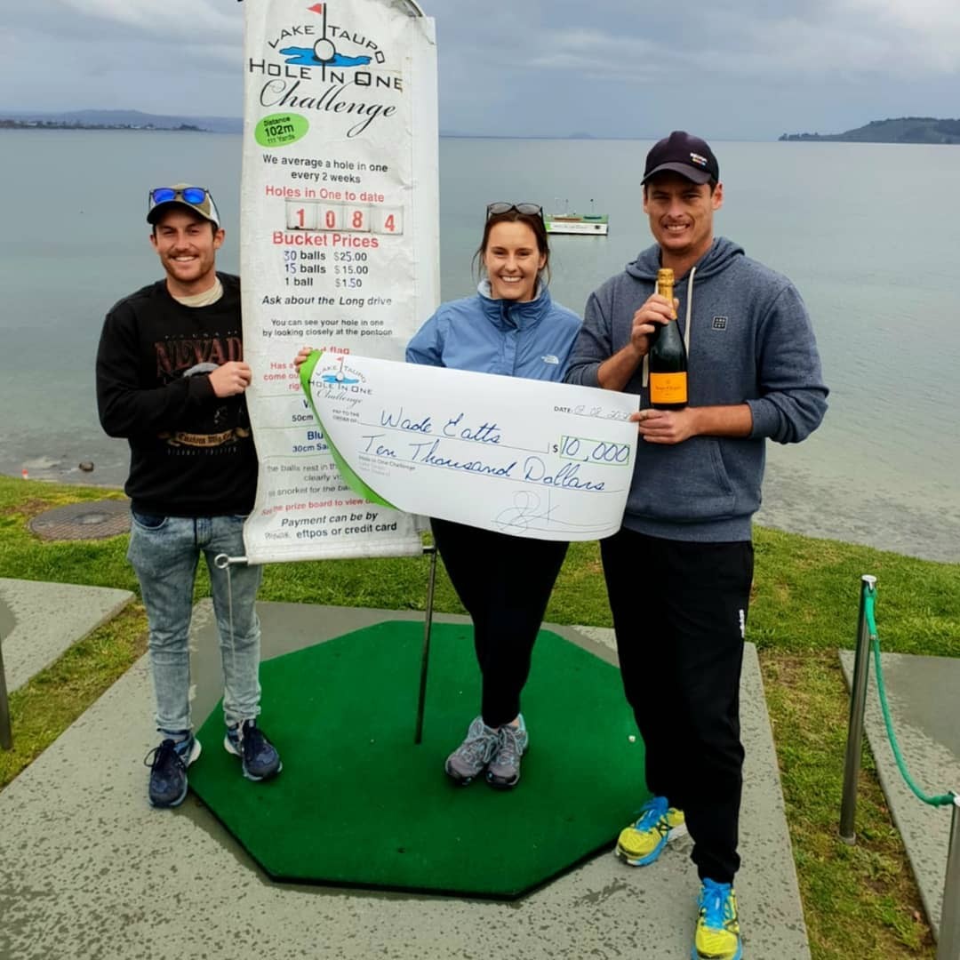 Three people hold up a novelty size cheque for $10,000 after hitting a hole in one at the Lake Taupo Golf Challenge.