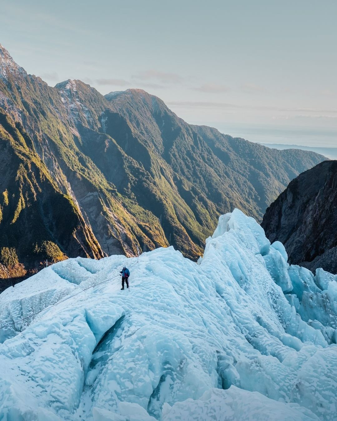 A person walks along a raised section of the Franz Josef glacier on a heli hike experience.