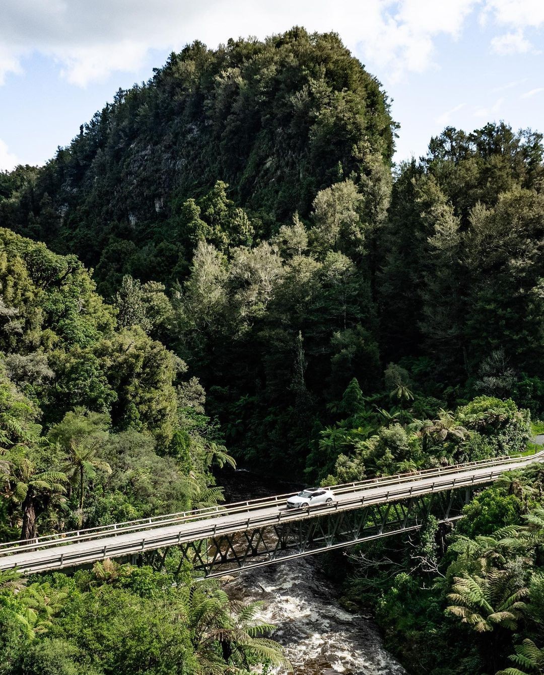 A car crosses a bridge with a river beneath on the Forgotten Highway, Taranaki.