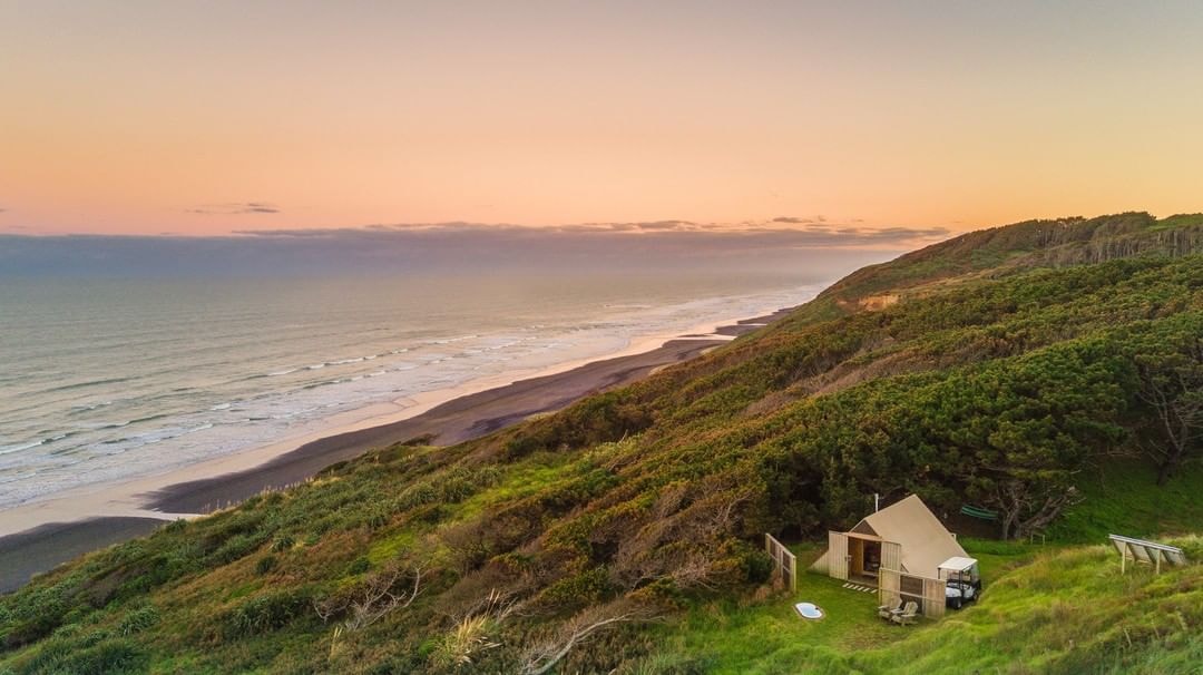 A Castaways Resort Glam Camping tent nestled amongst the coastal bush at sunset.