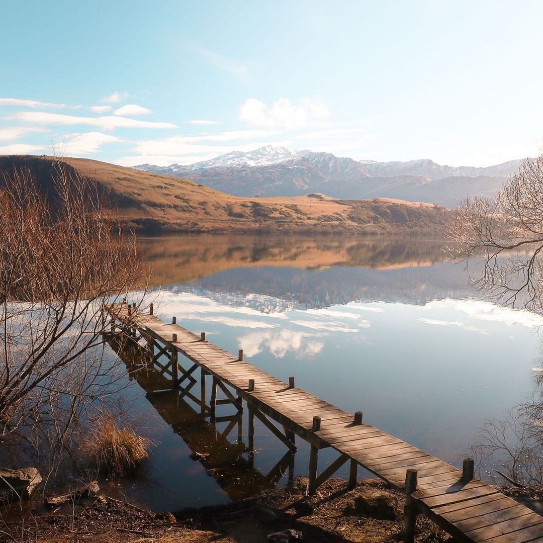 A mirror reflection of the surrounding mountains on Lake Hayes in Queenstown.