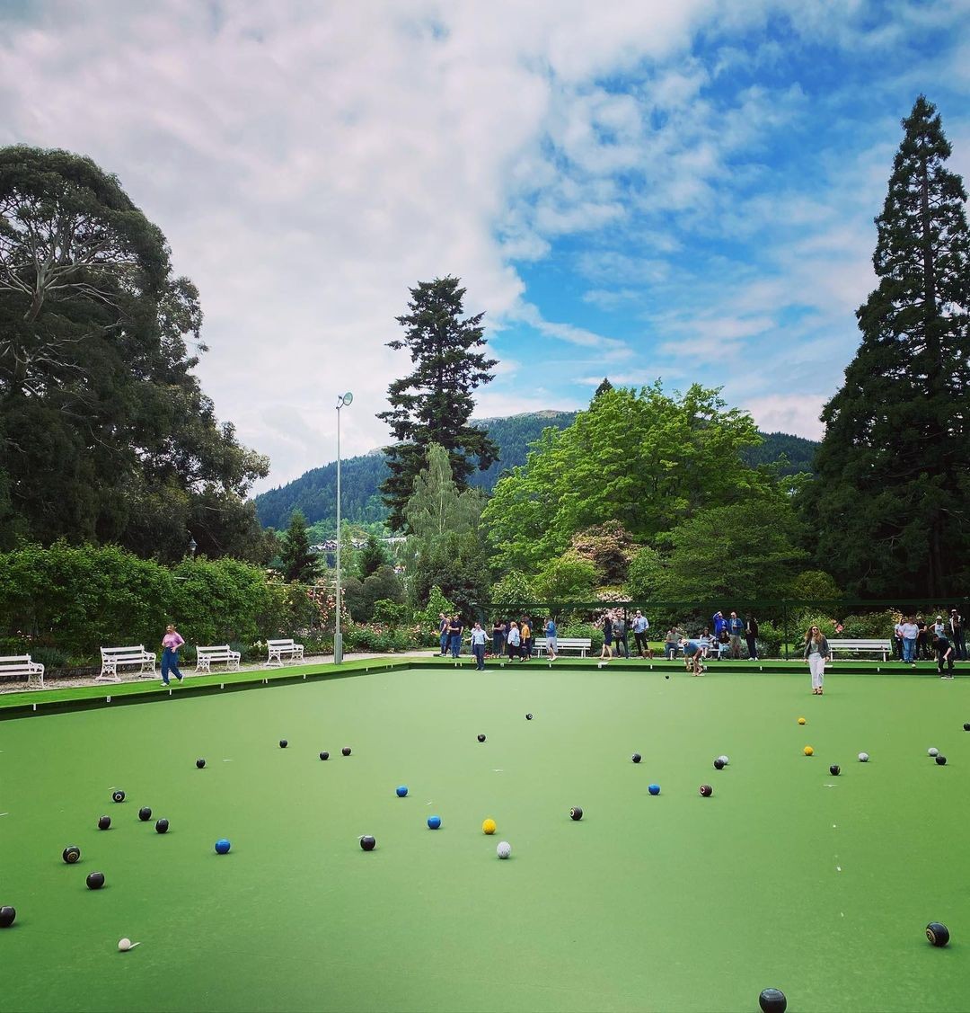 A large group of people enjoy a game of lawn bowls at the Queenstown Bowling Club located in the Queenstown Gardens.