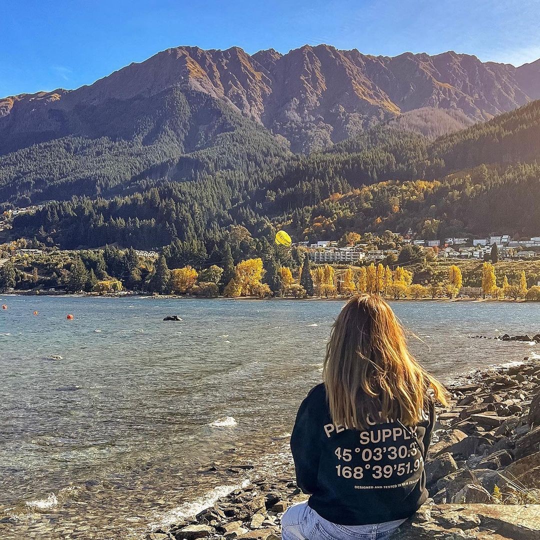 A woman sits and marvels at the views from the Queenstown Gardens rocky beach front.