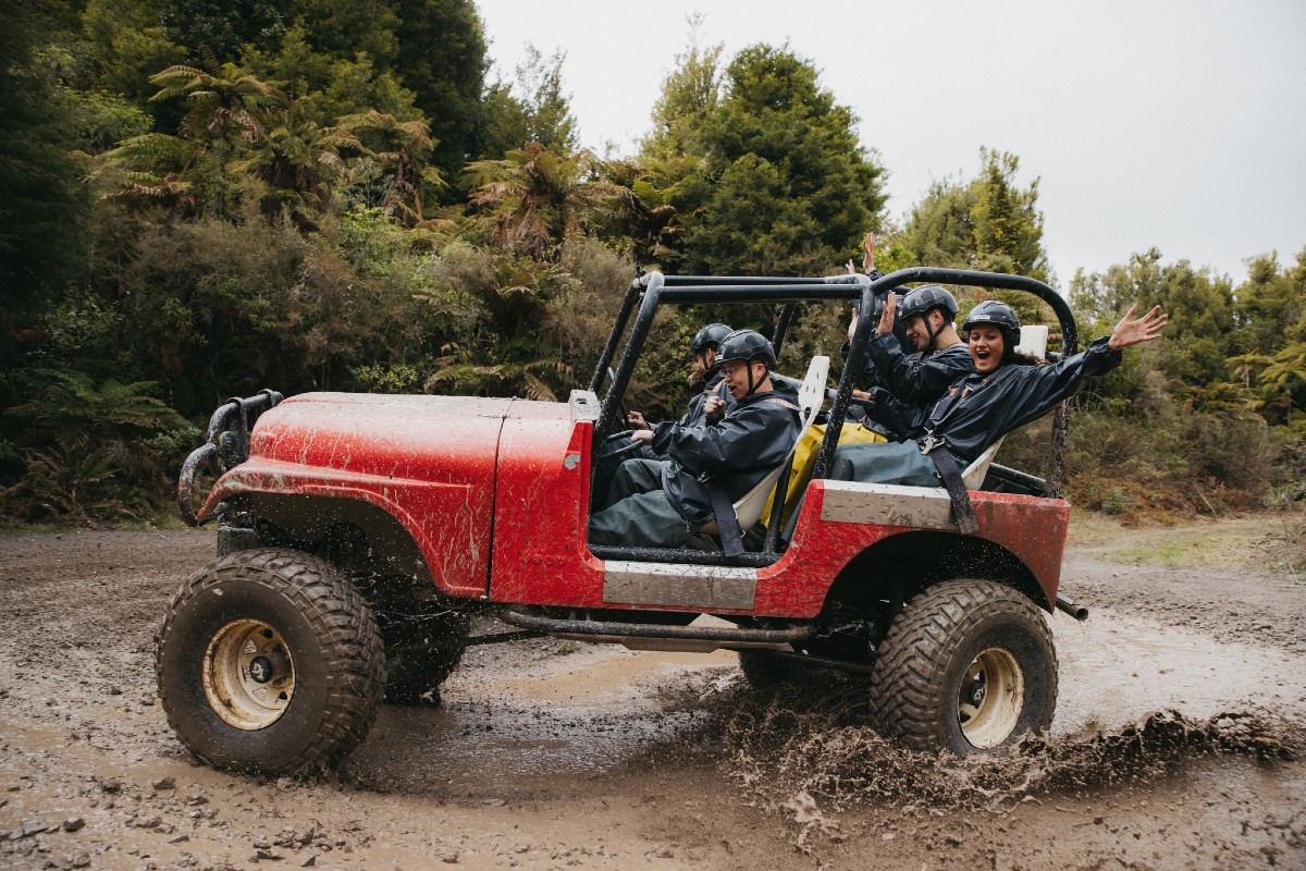 A group of thrill seeking customers ride through a large muddy puddle in a 4x4 vehicle at OffRoad NZ, Rotorua.