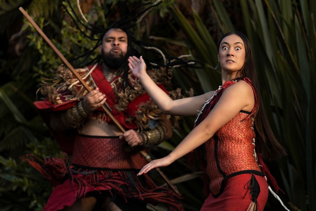 A man and woman of Māori descent perform a traditional welcoming dance to visitors at Te Pā Tū - Tamaki Māori Village.