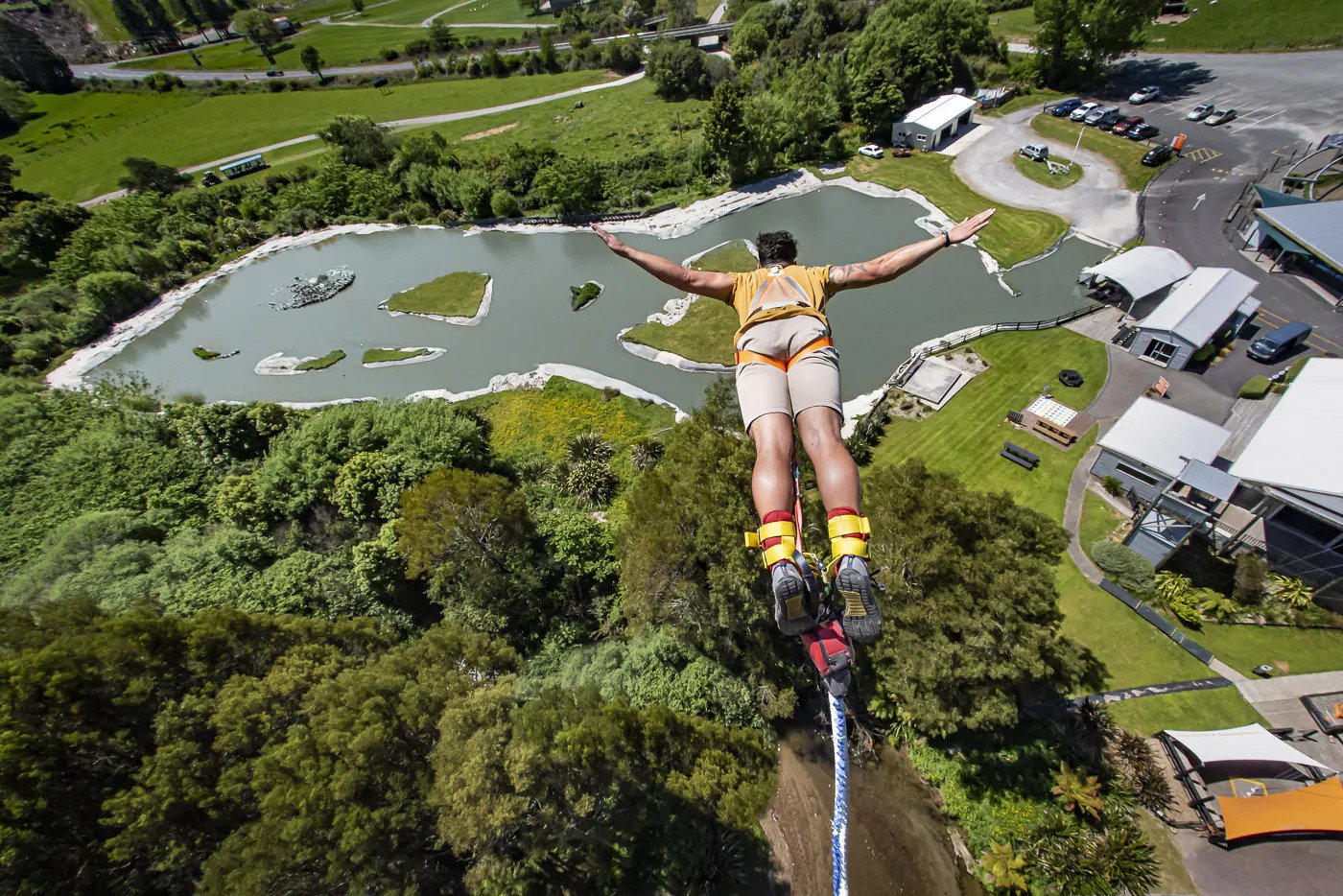 A man spreads his arms wide as he bungy jumps from a suspended platform at Velocity Valley Rotorua Adventure Park.