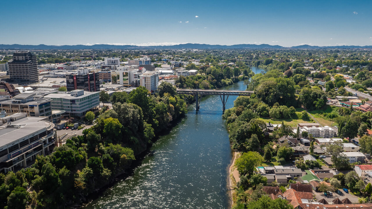 A stunning photo of the Waikato River intersecting Hamilton on a sunny day.