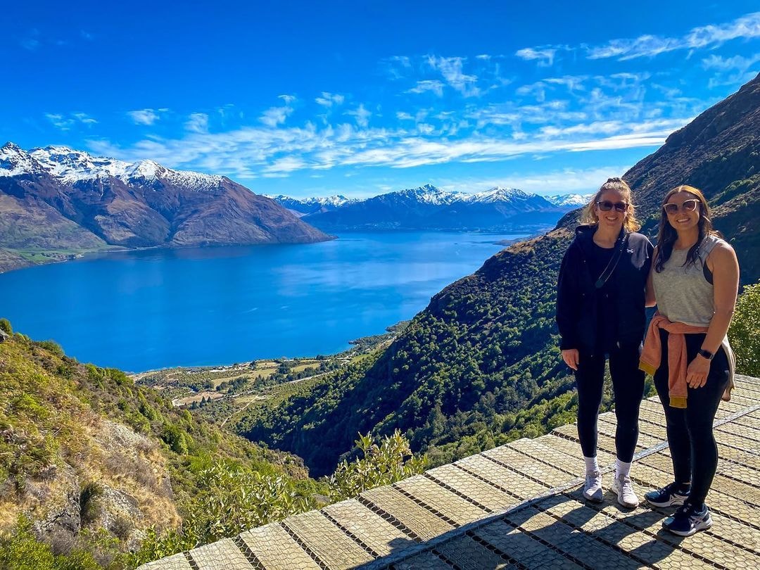 Two friends pose for a photo at the top of the Wye Creek walk overlooking Lake Whakatipu in Queenstown.