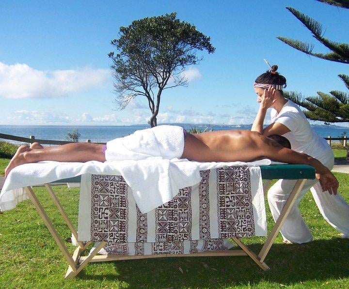 A women uses her elbow to massage a mans back on the side of Lake Rotorua at the Wikitoria Máori Healing centre.