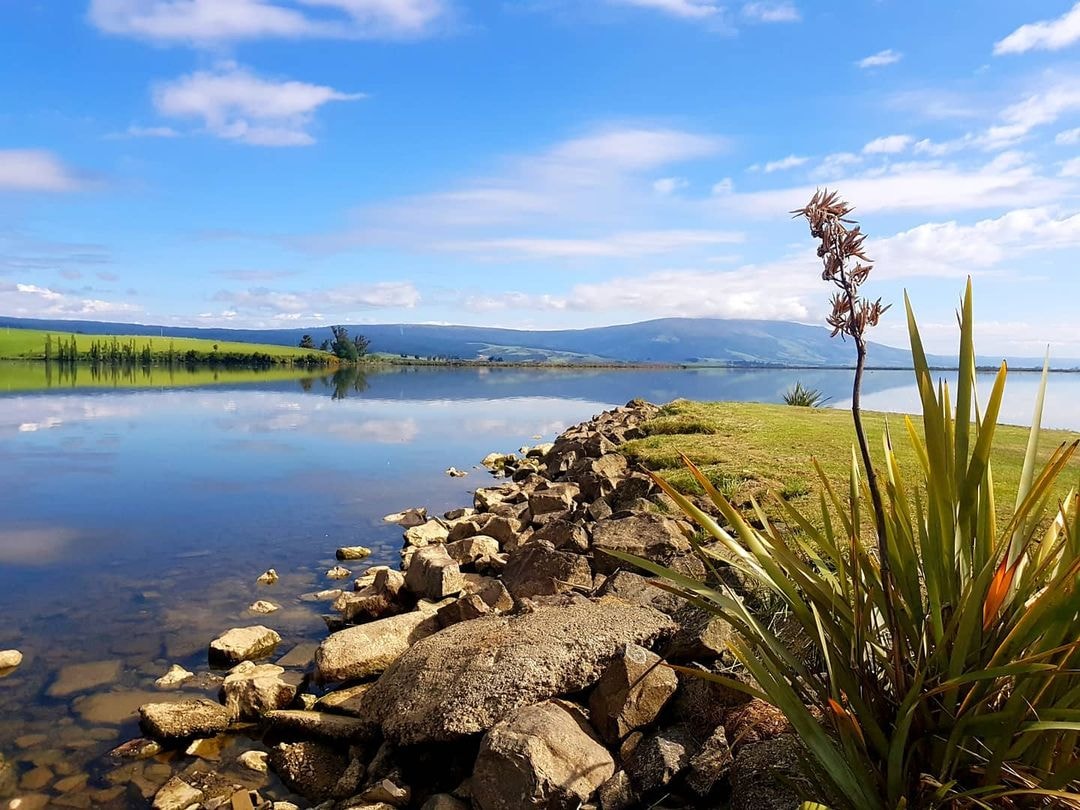 Lake Waihola on a calm day with mirror like reflections of the surrounding mountains.