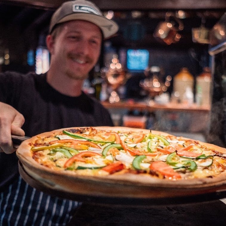 A chef serves up a fresh-out-the-oven pizza at The Cow Pizza & Spaghetti restaurant in Queenstown.
