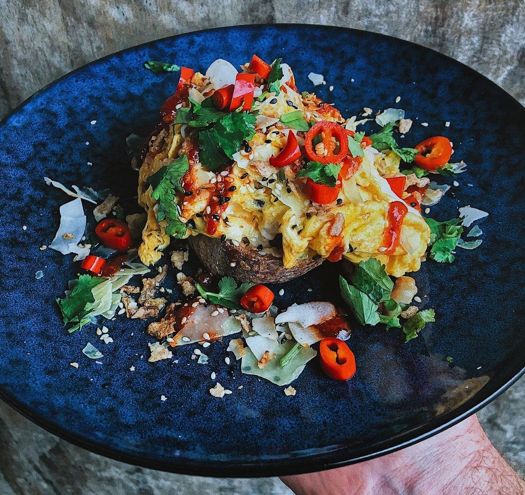 Chilli scrambled eggs on sourdough, parmesan, sambal dressing, toasted coconut, sesame seeds, crispy shallots, coriander, pickled red chilli served at Okere Falls Store Rotorua.