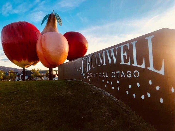 A sunrise capture of the Cromwell welcome sign with the enormous fruit sculptures in the background.