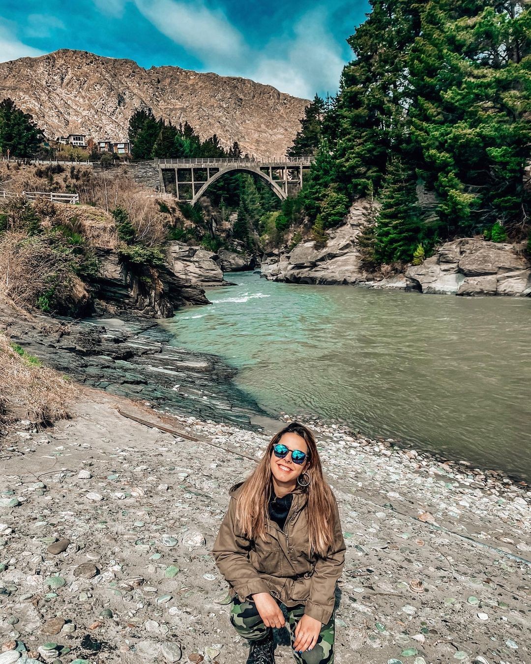 A woman poses in front of the Historic Edith Cavell bridge in Arthurs Point, Queenstown.