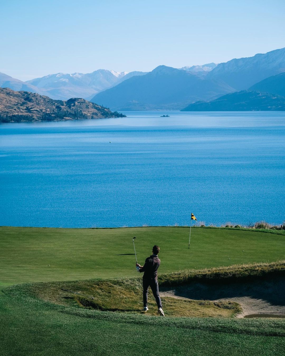 A golfer uses a wedge close to the green at the scenic Jack Point golf course.