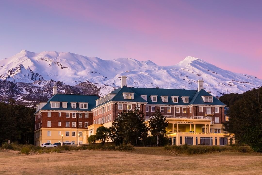 Chateau Tongariro in the twilight with Mount Ruapehu towering in the background covered in snow.