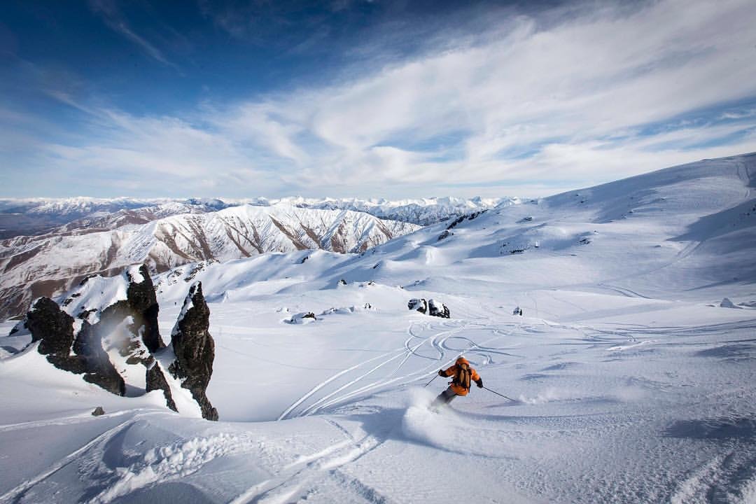 A skier descends a run in the Soho Basin on fresh powder with amazing views behind.