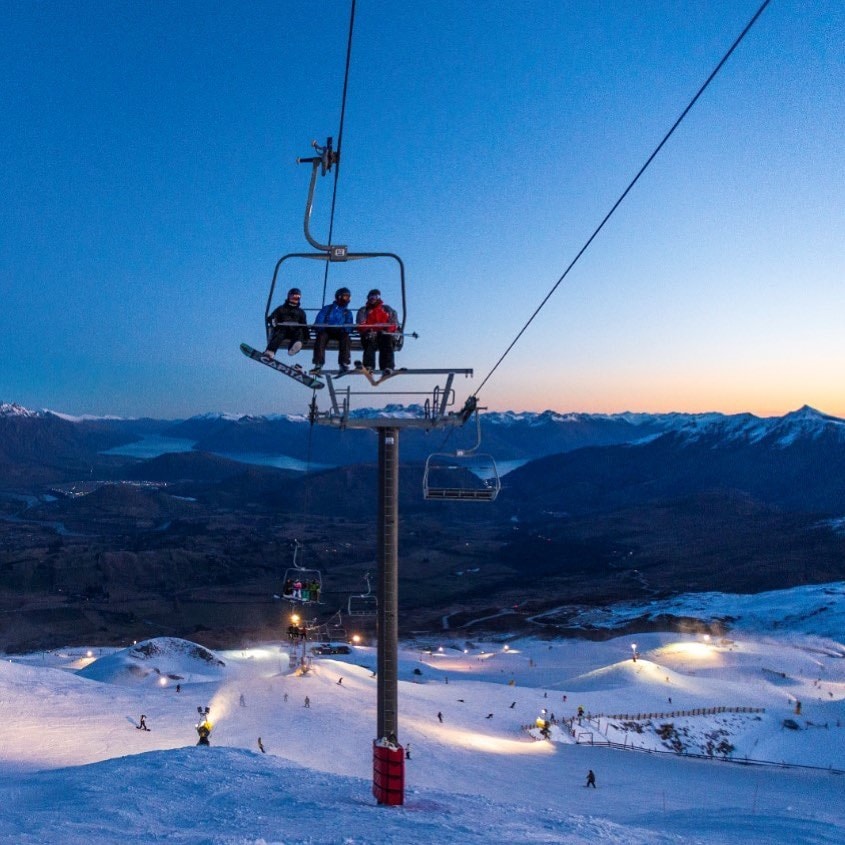 Three friends travel up the Coronet Peak chairlift in Queenstown.
