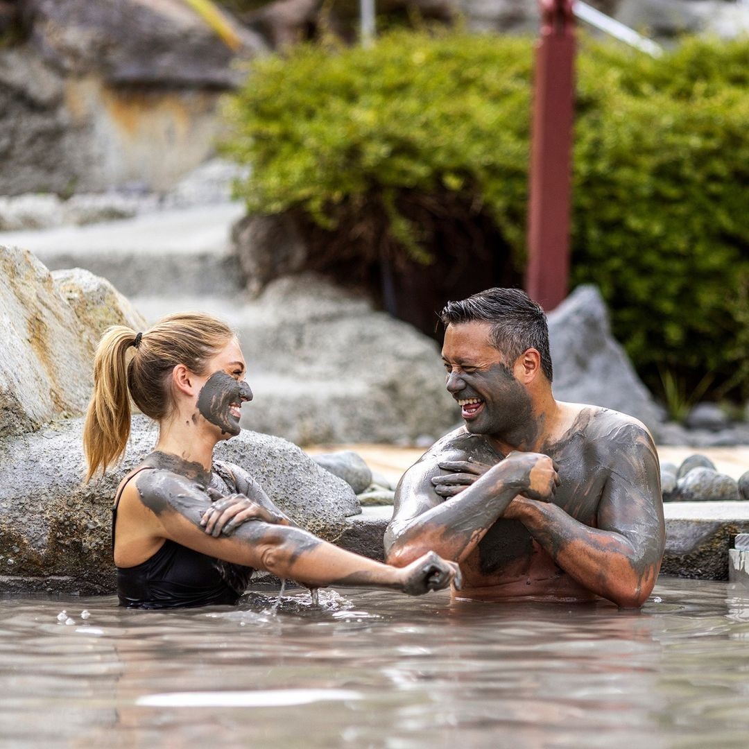 A couple laughs as they put mud on themselves at Rotorua's Hell's Gate