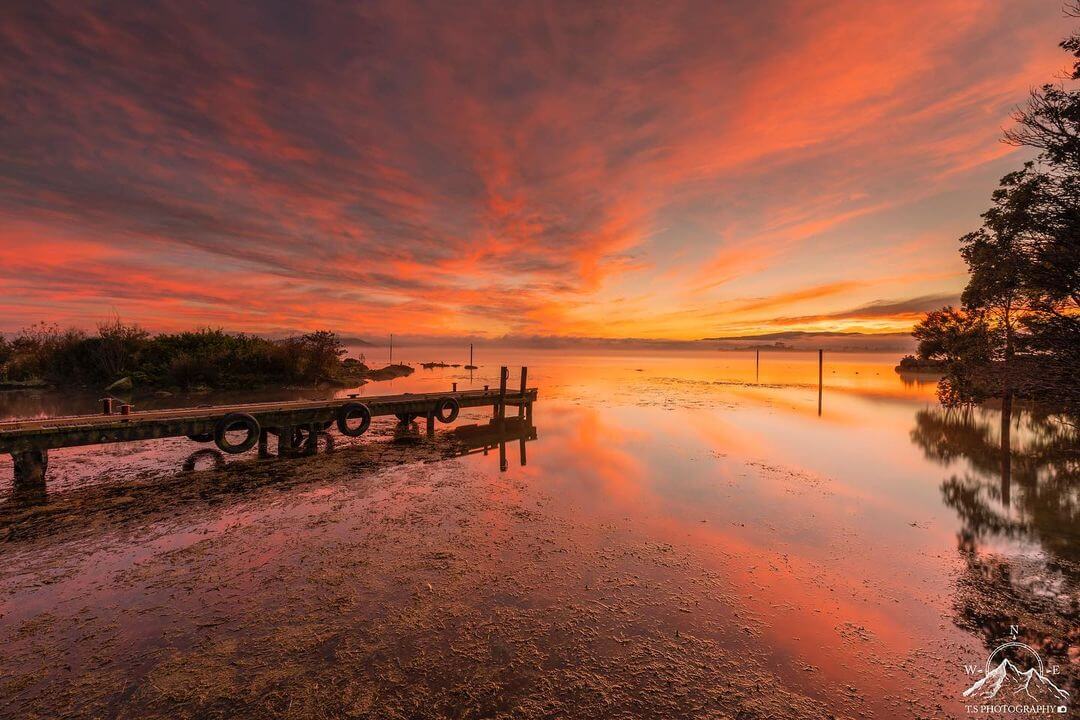 Scenic shot of lake Rotorua with a colourful sunset illuminating the sky.