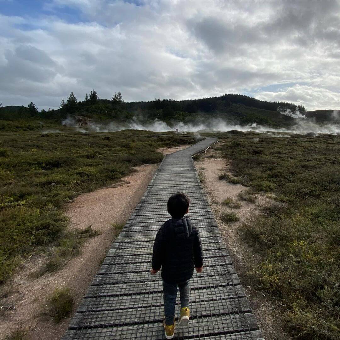 Child about to walk past a bubbling geothermal pool at Craters of the moon Taupo.