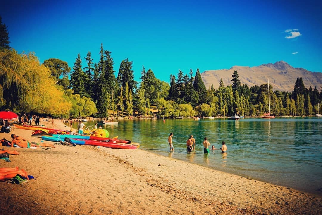 People swimming at the Queenstown lake front on a Summers day.