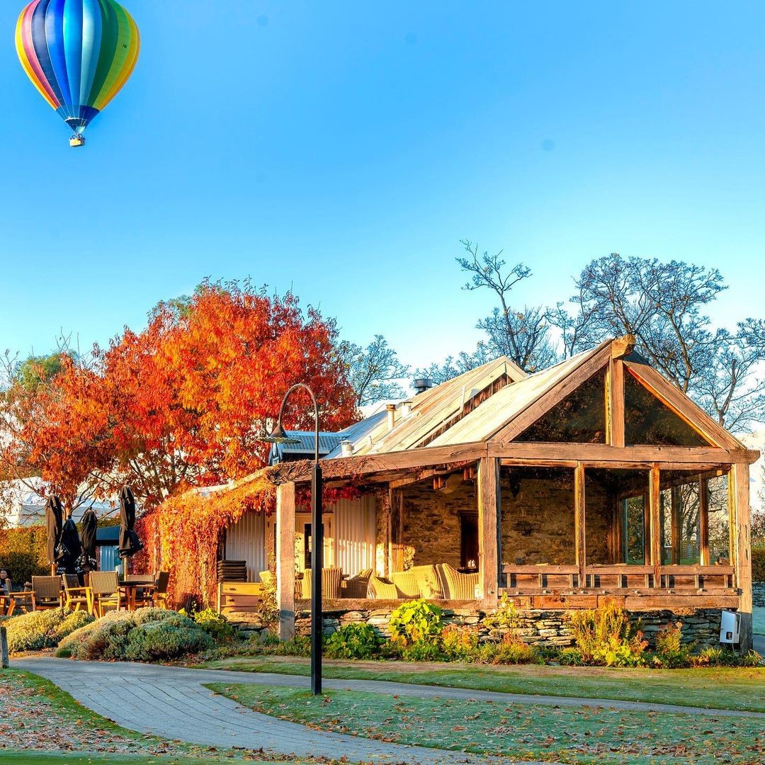 Arrowtown in all its Autumn beauty, with a Hot Air Balloon flying in the background.