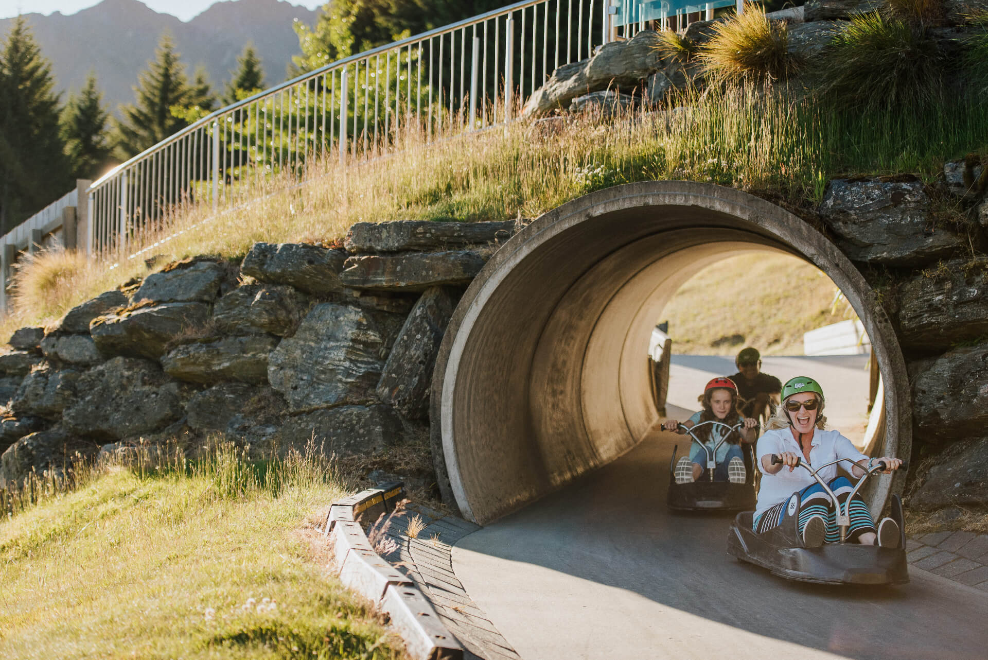 A family smiles as they race through a tunnel on the Scenic Luge track at Skyline Queenstown.