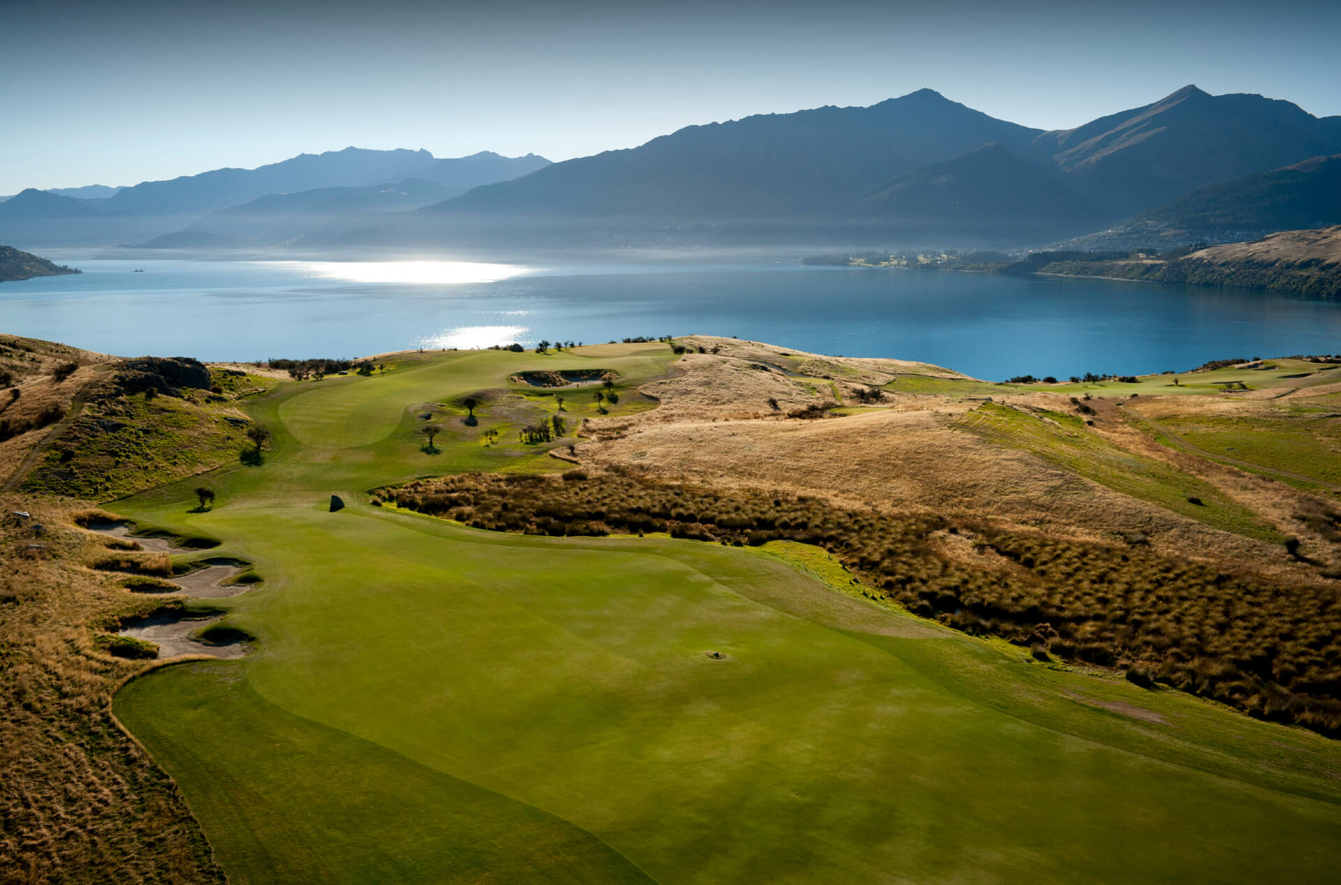 An aerial photo of the Jacks point golf course with views of Lake Wakatipu and surrounding mountains in the background.