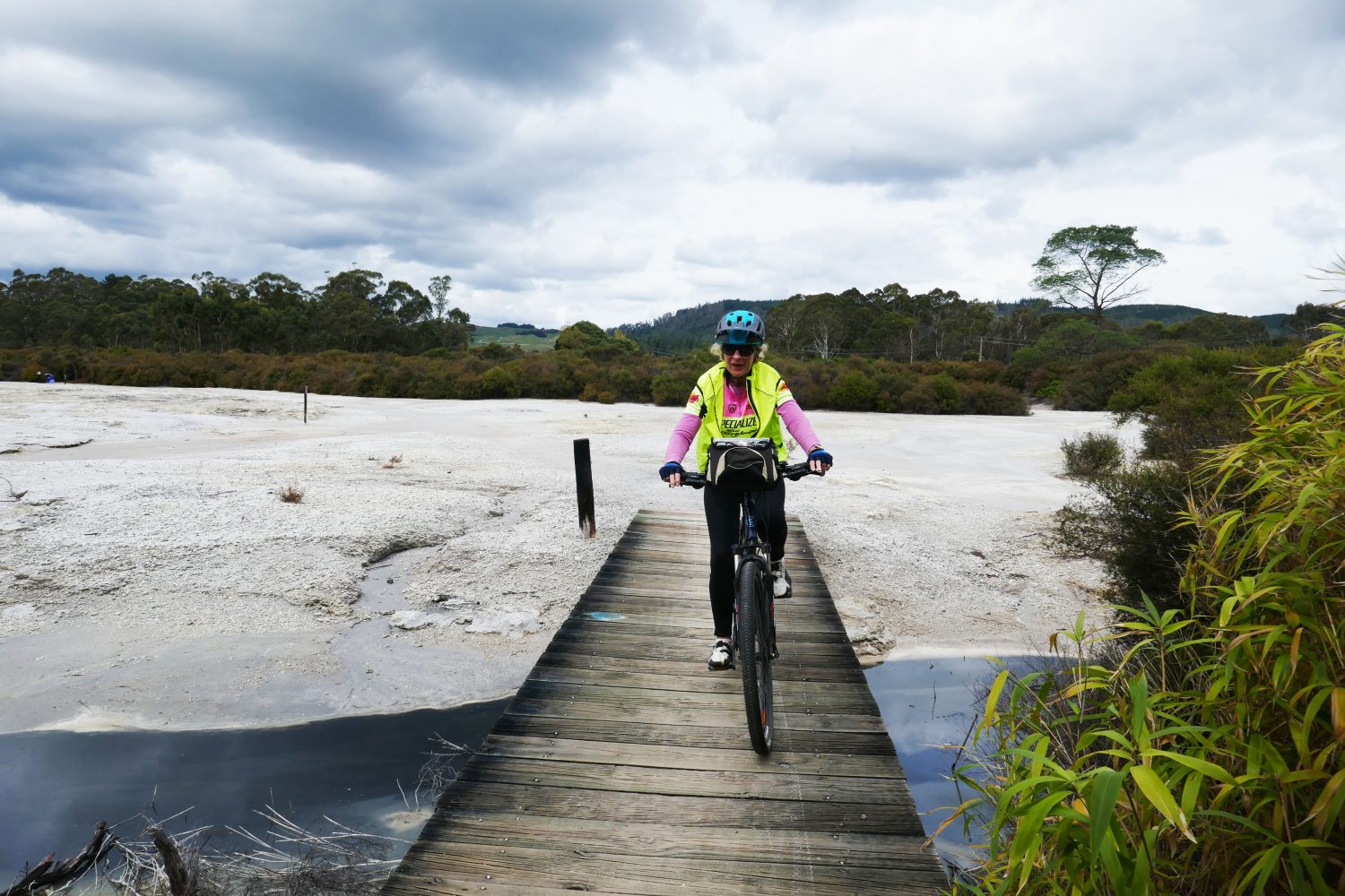 A lady crosses a small bridge on her mountain bike along the Sulphur Bay track.
