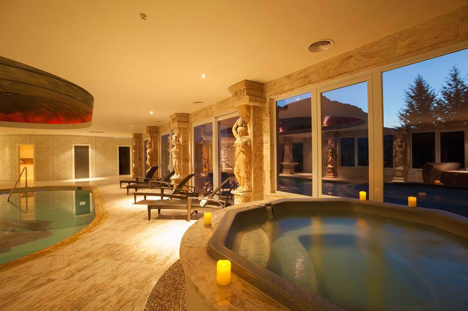 An indoor spa pool surrounded by candles and yellow lighting.