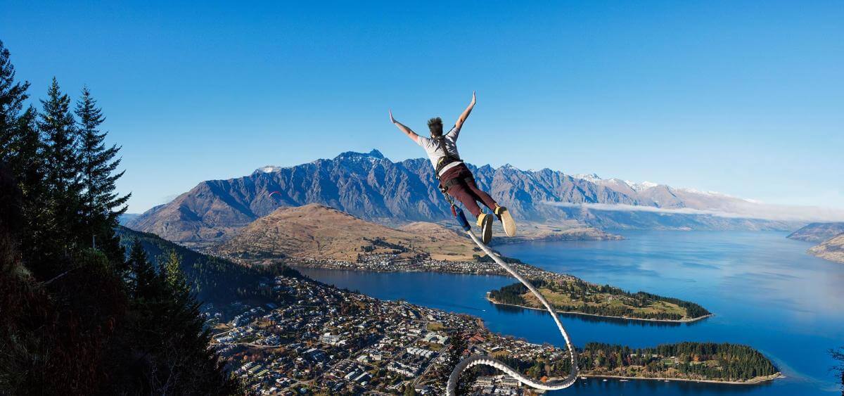 A person leaps into the sky above Queenstown attached to a bungy cord at the Ledge Bungy.