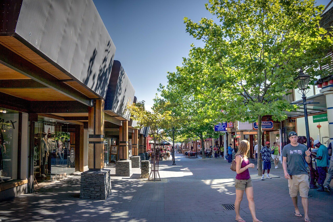 Queenstown Mall is filled with people, green trees, and blue skies.