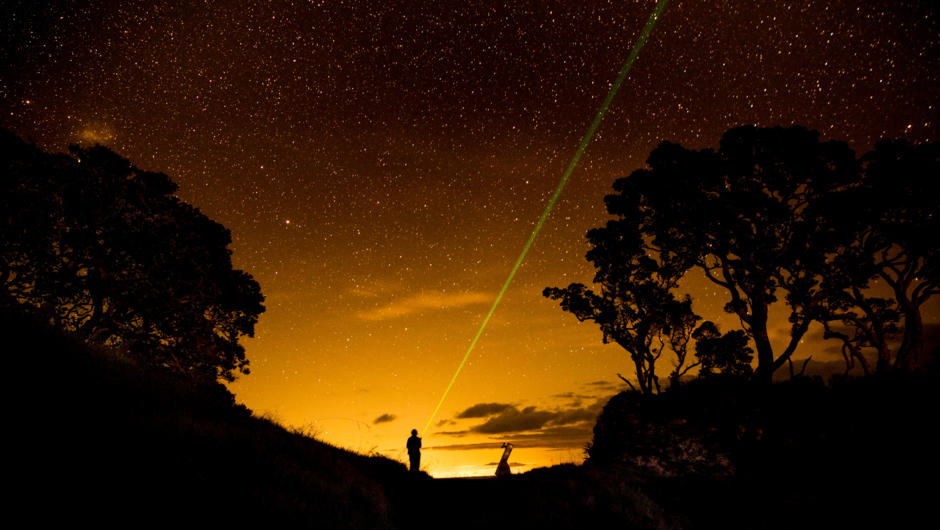 A person shines a laser beam across a night sky, point at the constellations that light up the sky above.