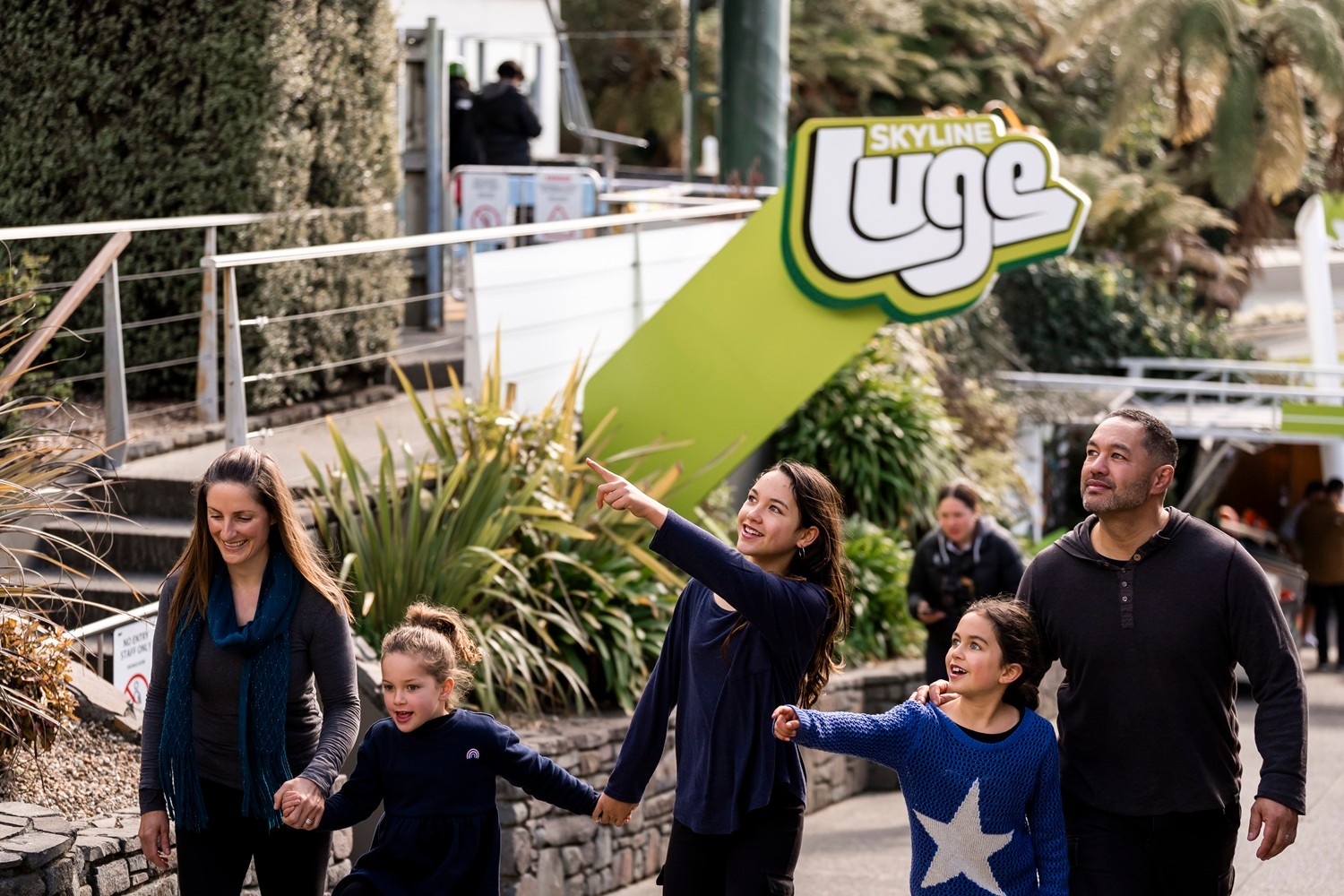 A women points excitedly at a sign near the start of the Skyline Luge tracks at Skyline Rotorua.