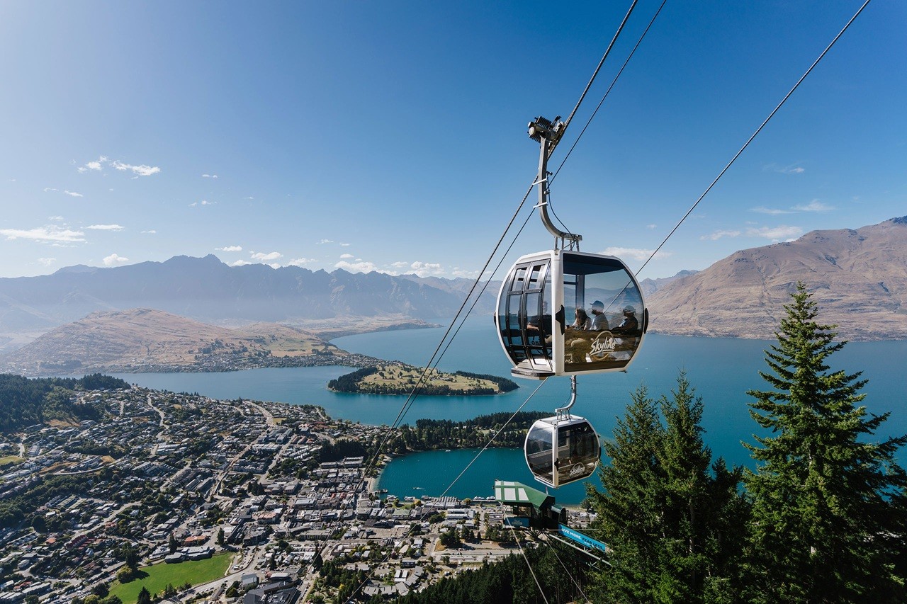A Gondola cabin nears the top complex of Skyline Queenstown with stunning panoramic views behind.