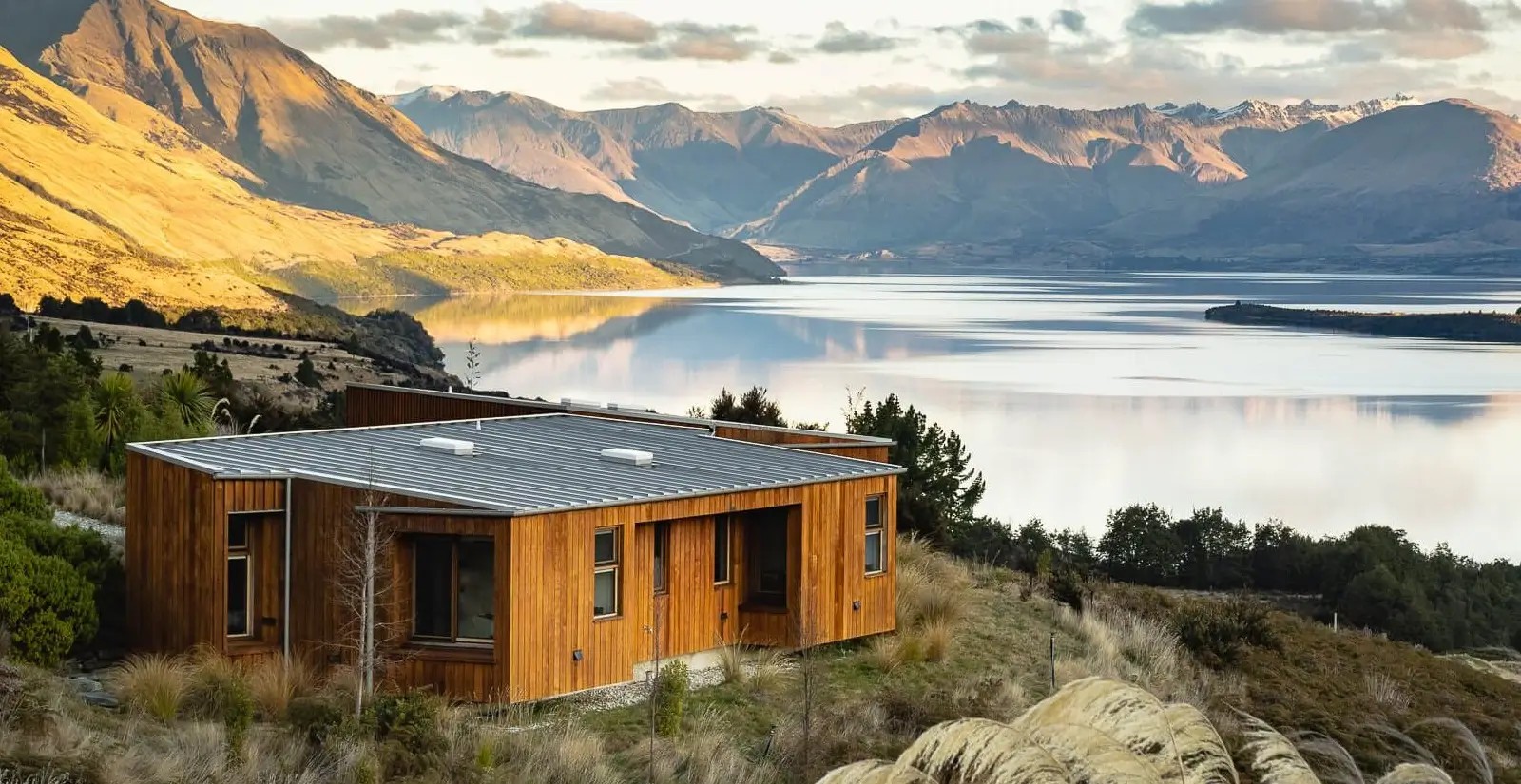 A wooden building in the wilderness, surrounded by a lake and some mountains in the Queenstown area.