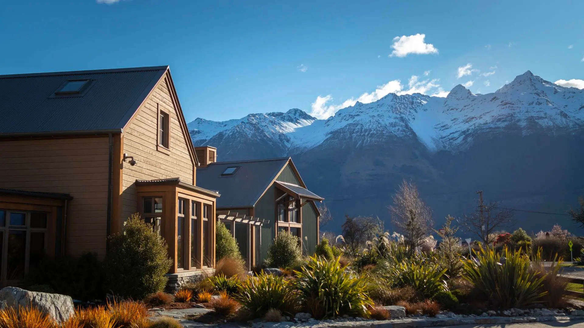 Two wooden buildings in front of mountains in the Queenstown area.